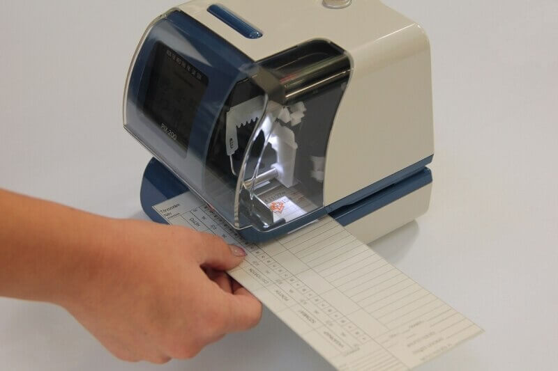 The Amano Time Stamp clock-in machine in the process of stamping someone's time card